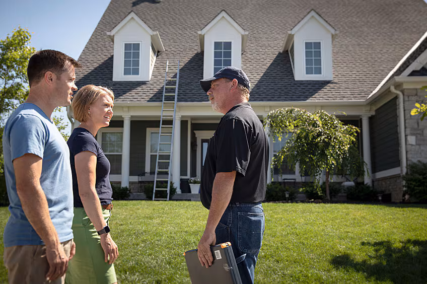 Roofing contractor discussing storm damage repair options with a homeowner